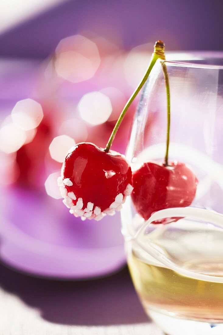 Cherries coated in sugar on the side of a glass