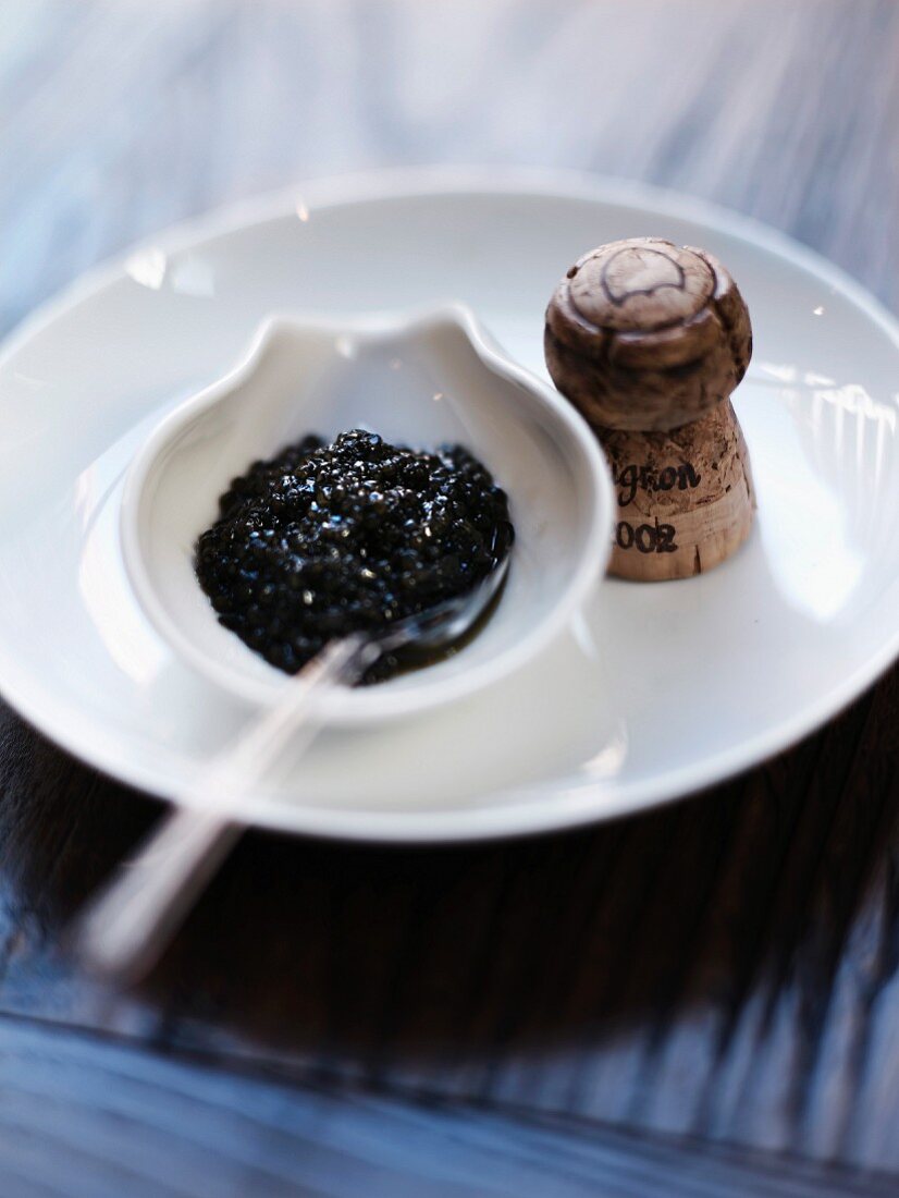 A bowl of caviar and a cork from a bottle of Dom Pérignon