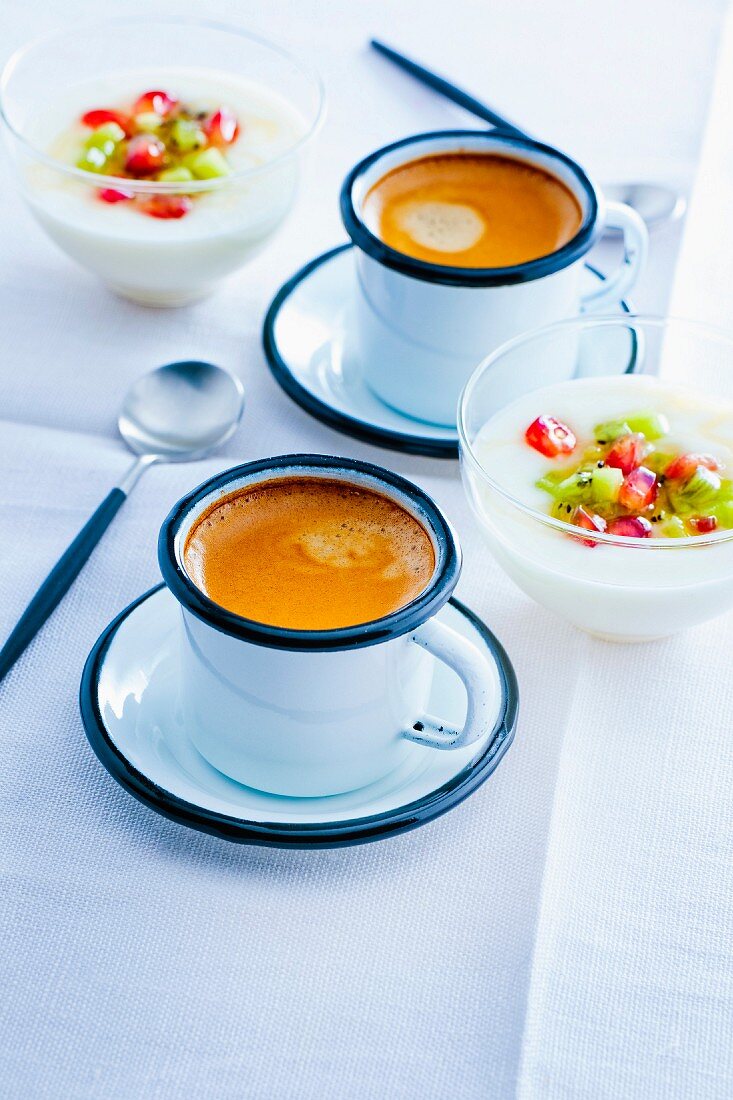 Cups of expresso coffee and a bowl of yoghurt with fresh fruit