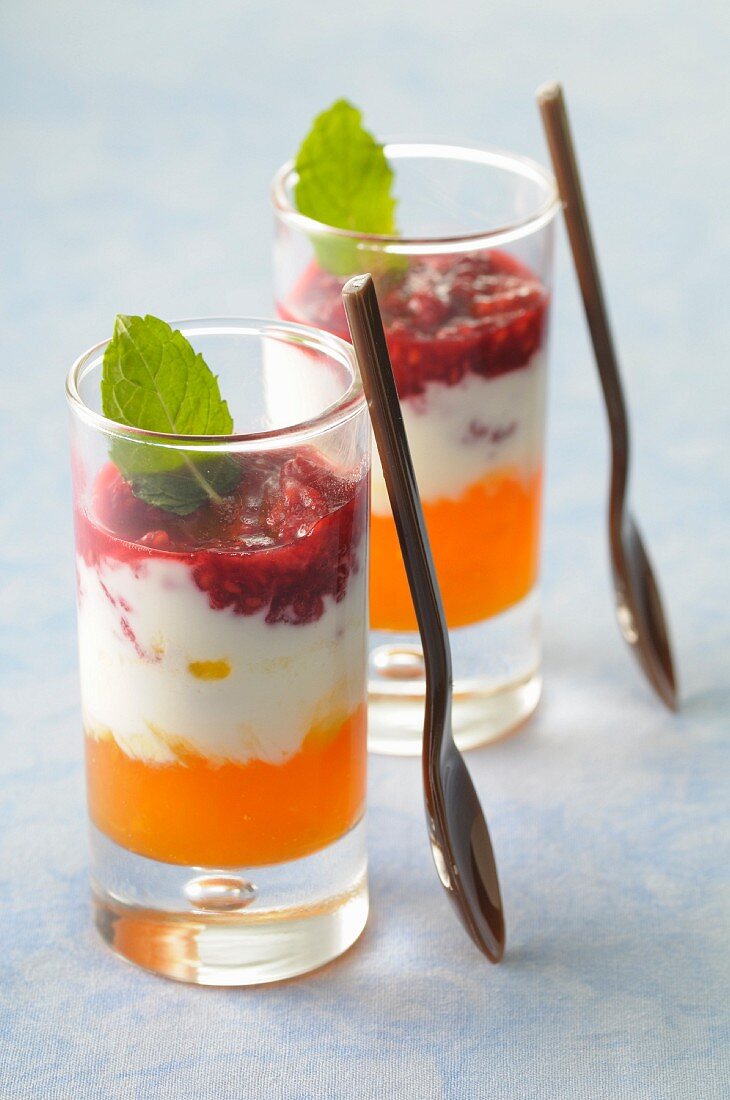 Joghurtdessert mit Himbeerpüree und Mangosirup im Glas