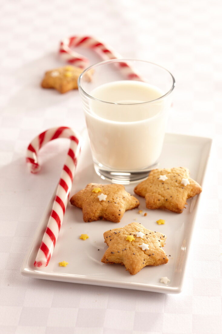 Sternförmige Weihnachtsplätzchen, Glas Milch und Zuckerstange