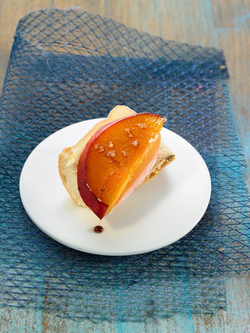 Cow's milk cheese on a slice of bread and topped with a slice of nectarine
