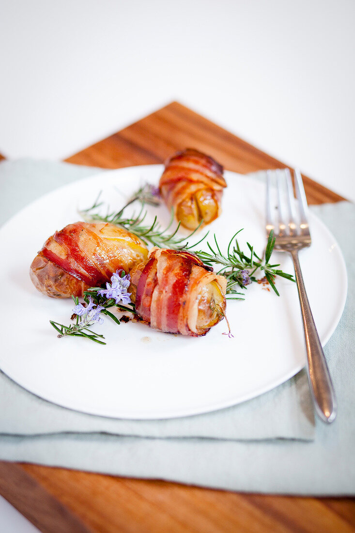 Baked potatoes wrapped in bacon with rosemary
