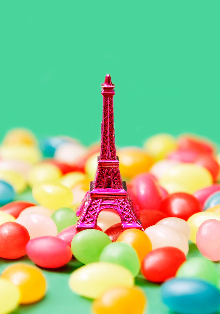 Composition with a mini pink Eiffel Tower and jelly beans on a green background