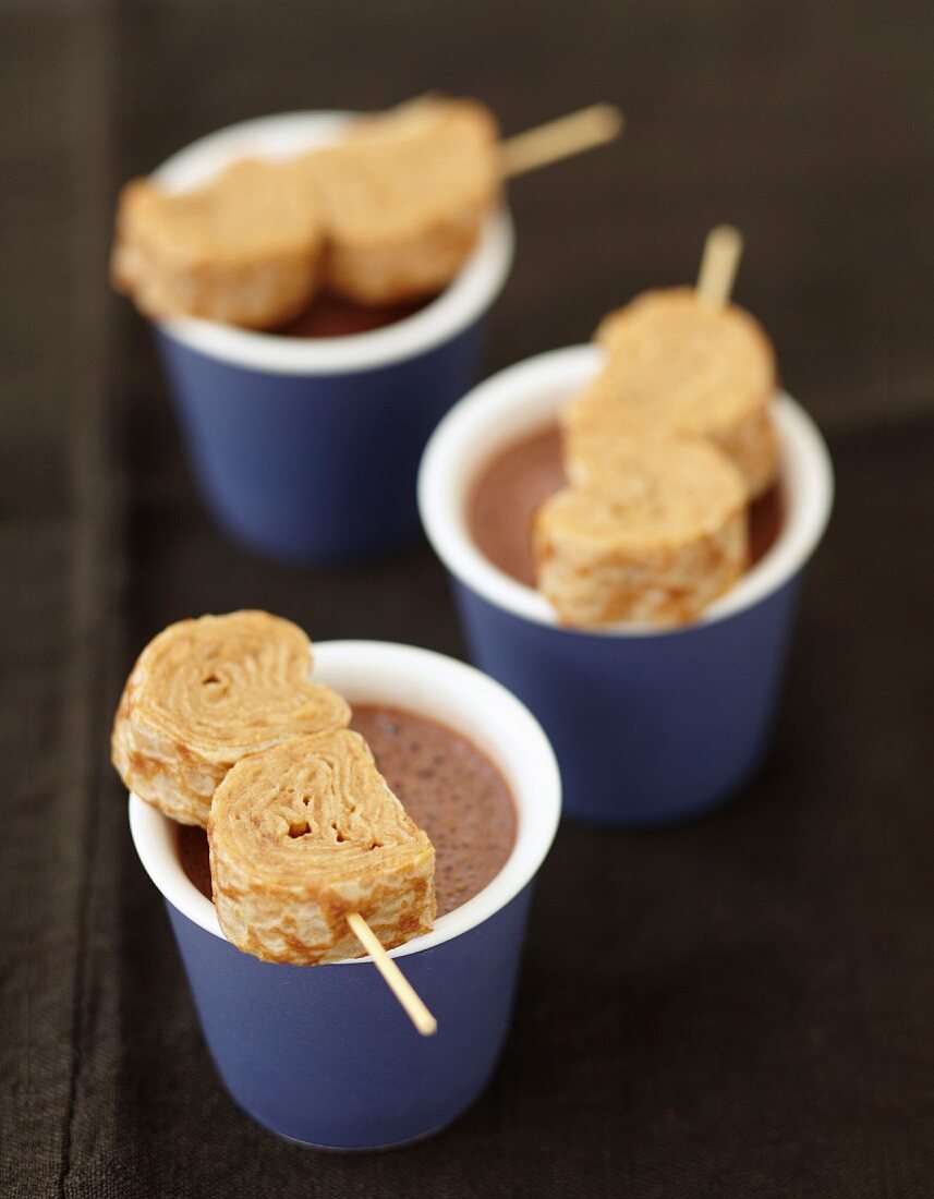 Pfannkuchenröllchen mit Milchkonfitüre auf heißer Schokolade