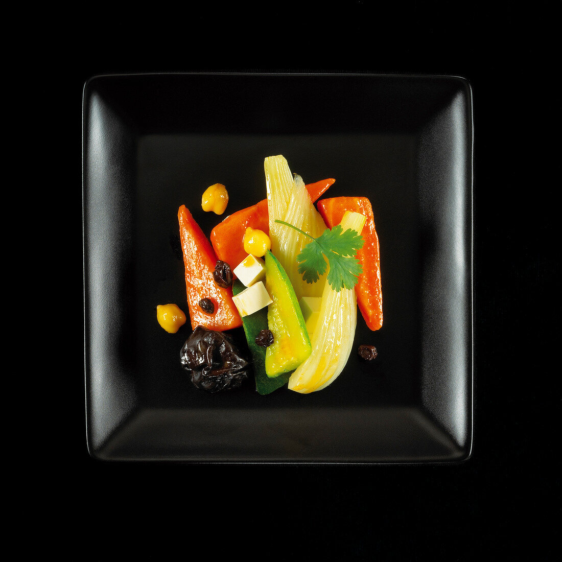 Vegetarian dish of stewed vegetables with dried fruit and vegetables on a black background