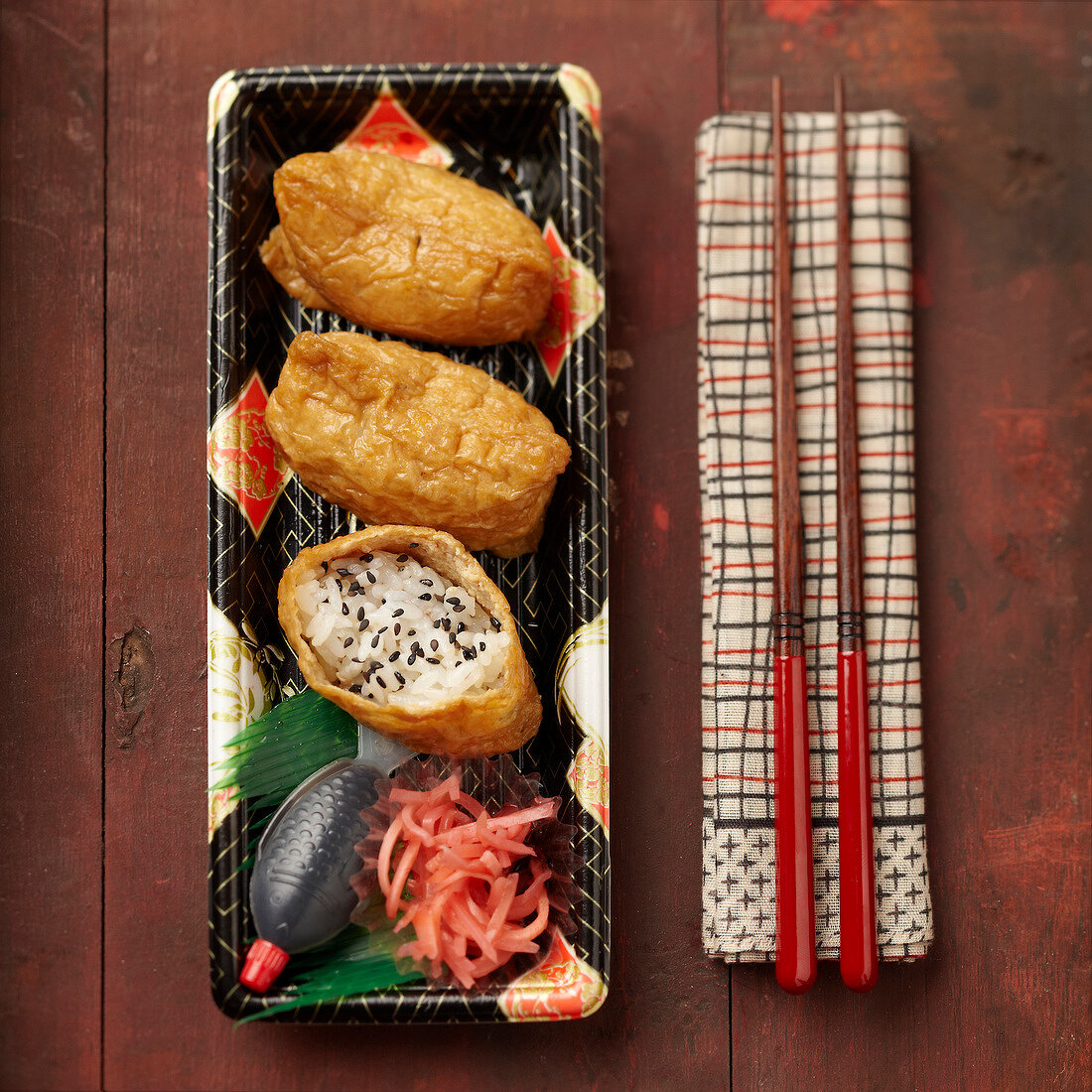Inari Sushi auf japanischem Geschirr mit Stäbchen