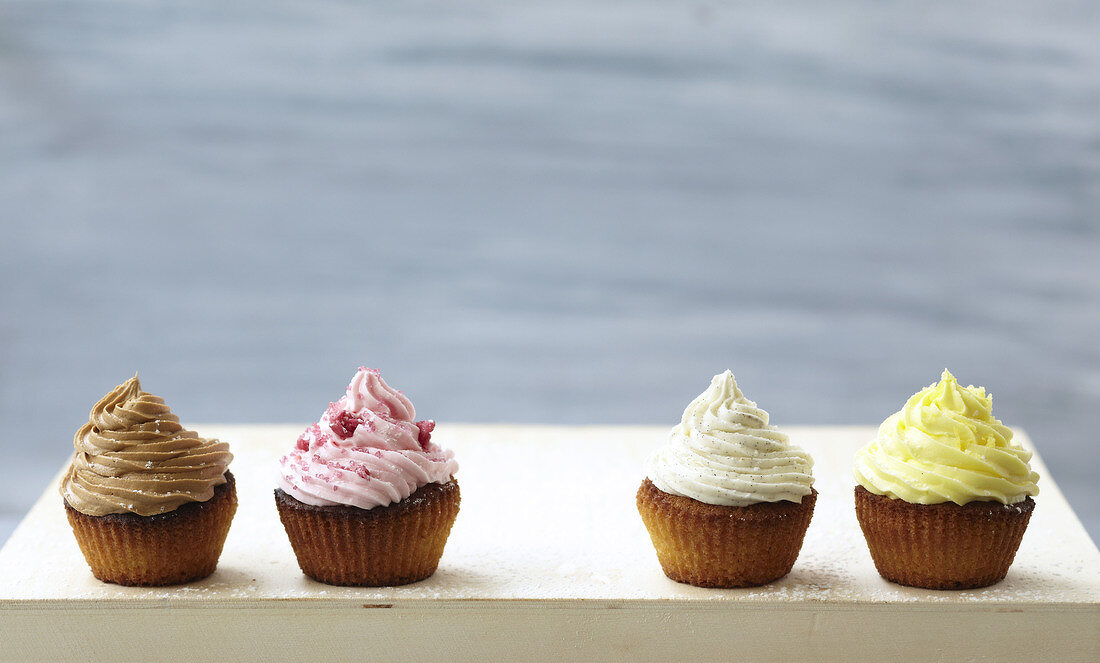 Vier Cupcakes mit verschiedenen Toppings