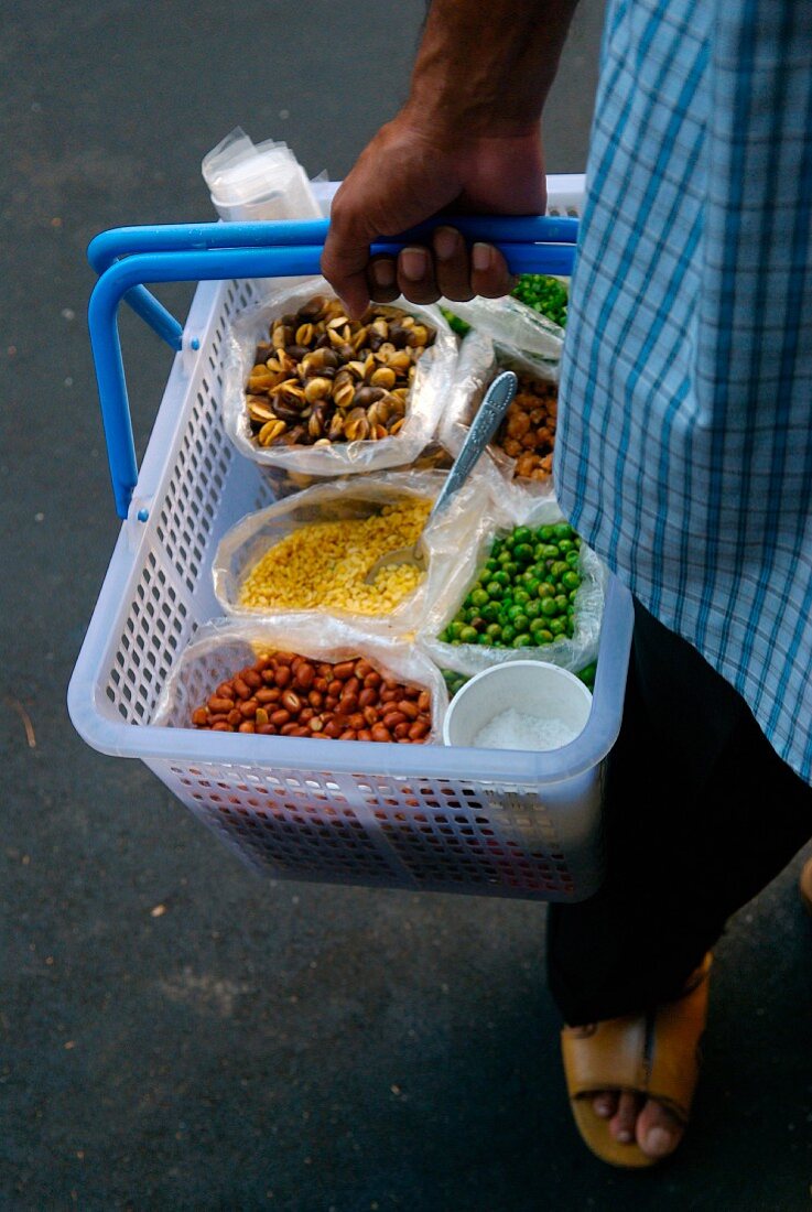Strassenverkäufer mit Korb getrocknetem Gemüse