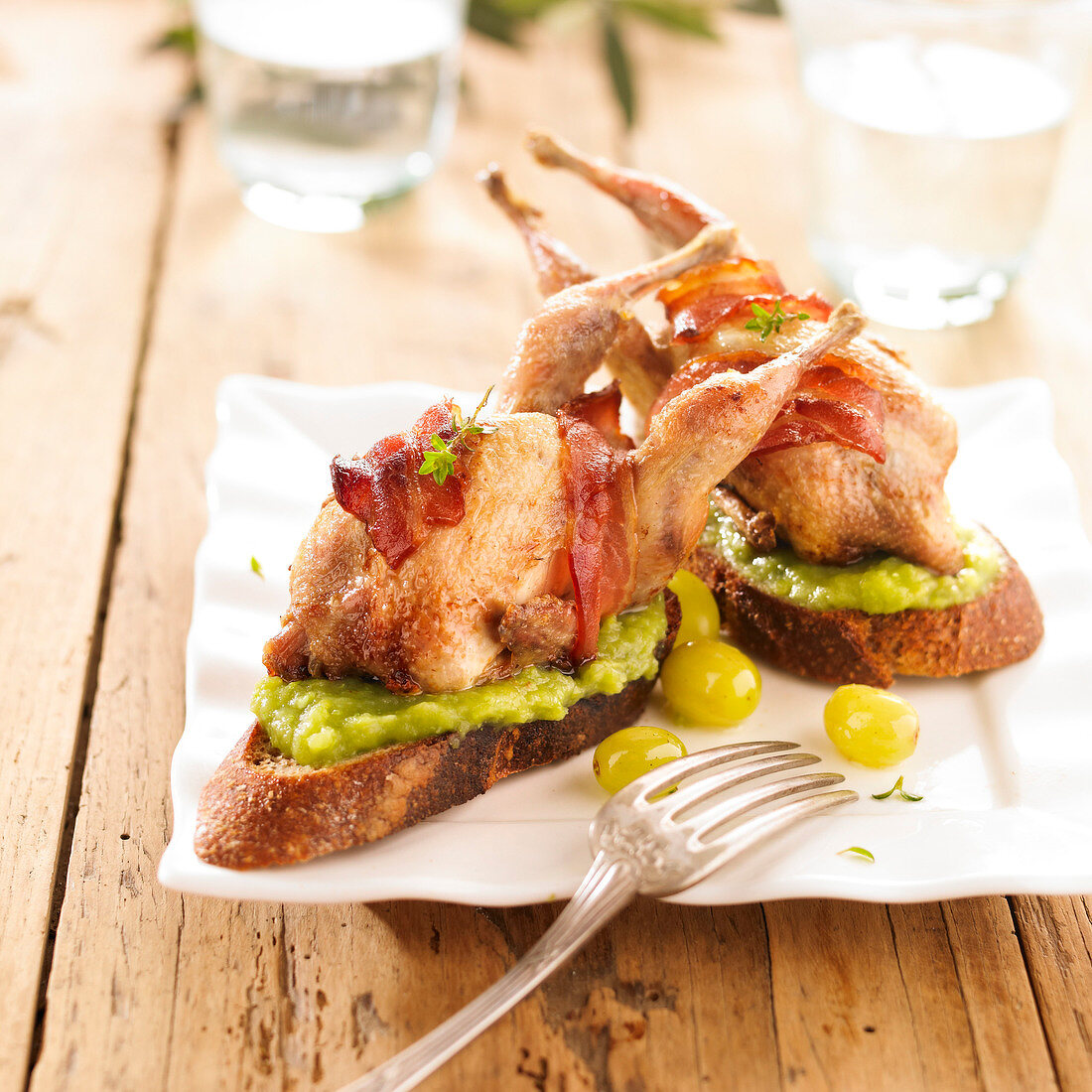 Roasted quail with bacon and tomato on guacamole toasts