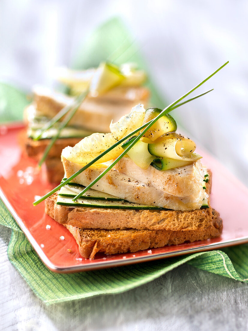 Belegtes Brot mit Hähnchenstreifen, eingelegter Zitrone und Zucchini