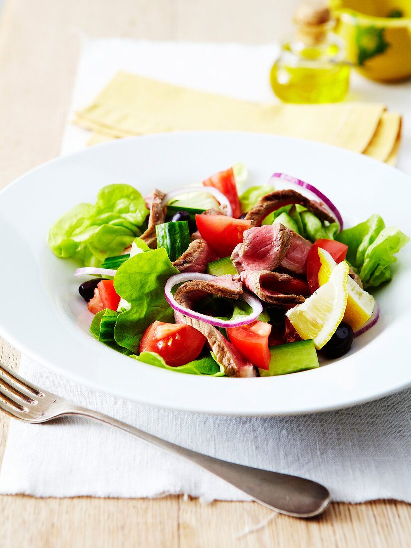 Salat mit Tomaten, Gurke, Oliven und mariniertem Rindfleisch