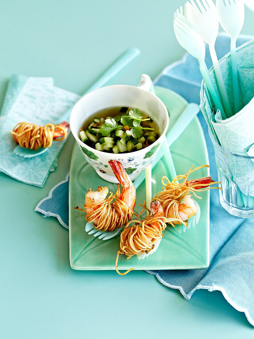 Fried scampis wrapped in noodles and a small bowl of chilled cucumber broth