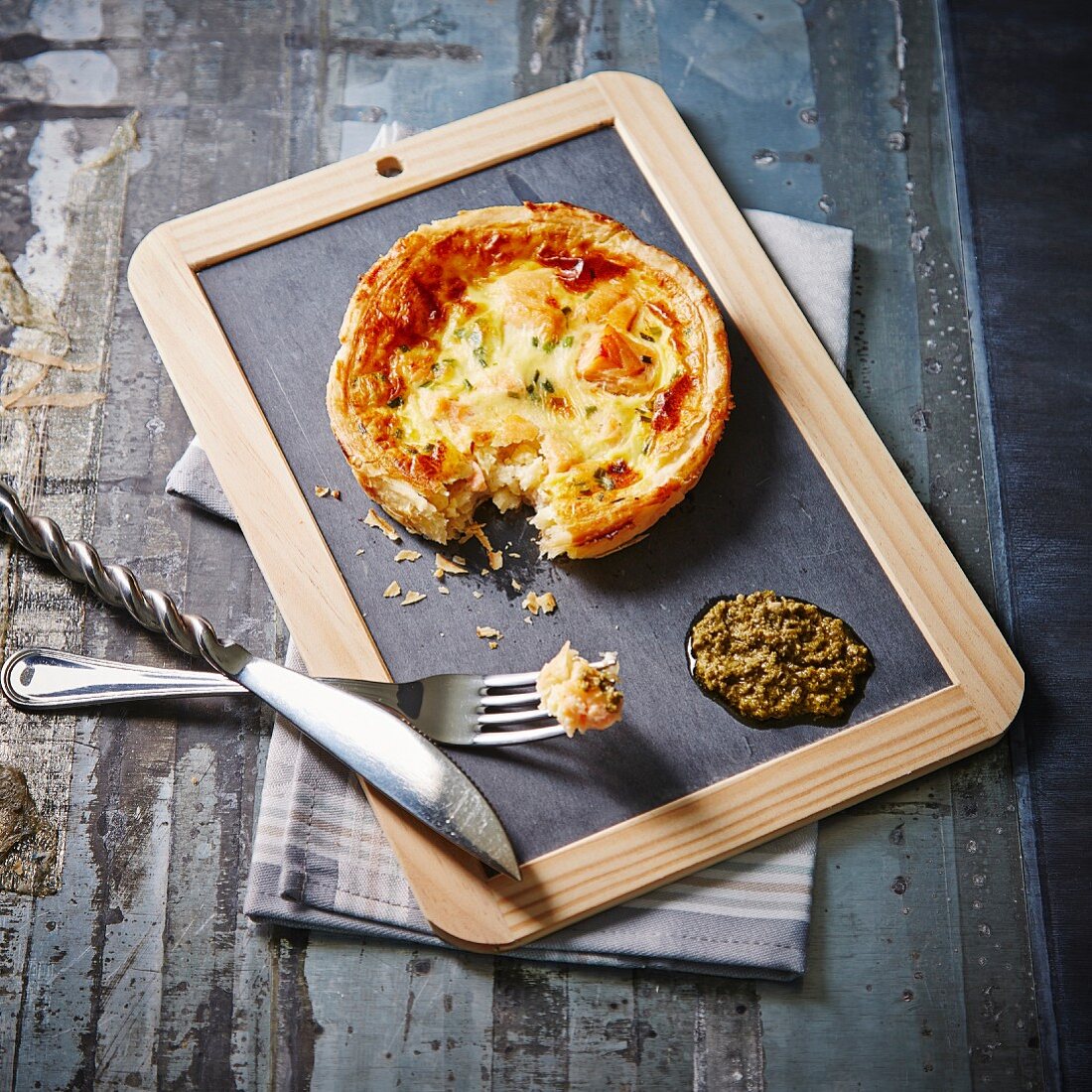 Individual salmon quiche and green tapenade on a slate blackboard