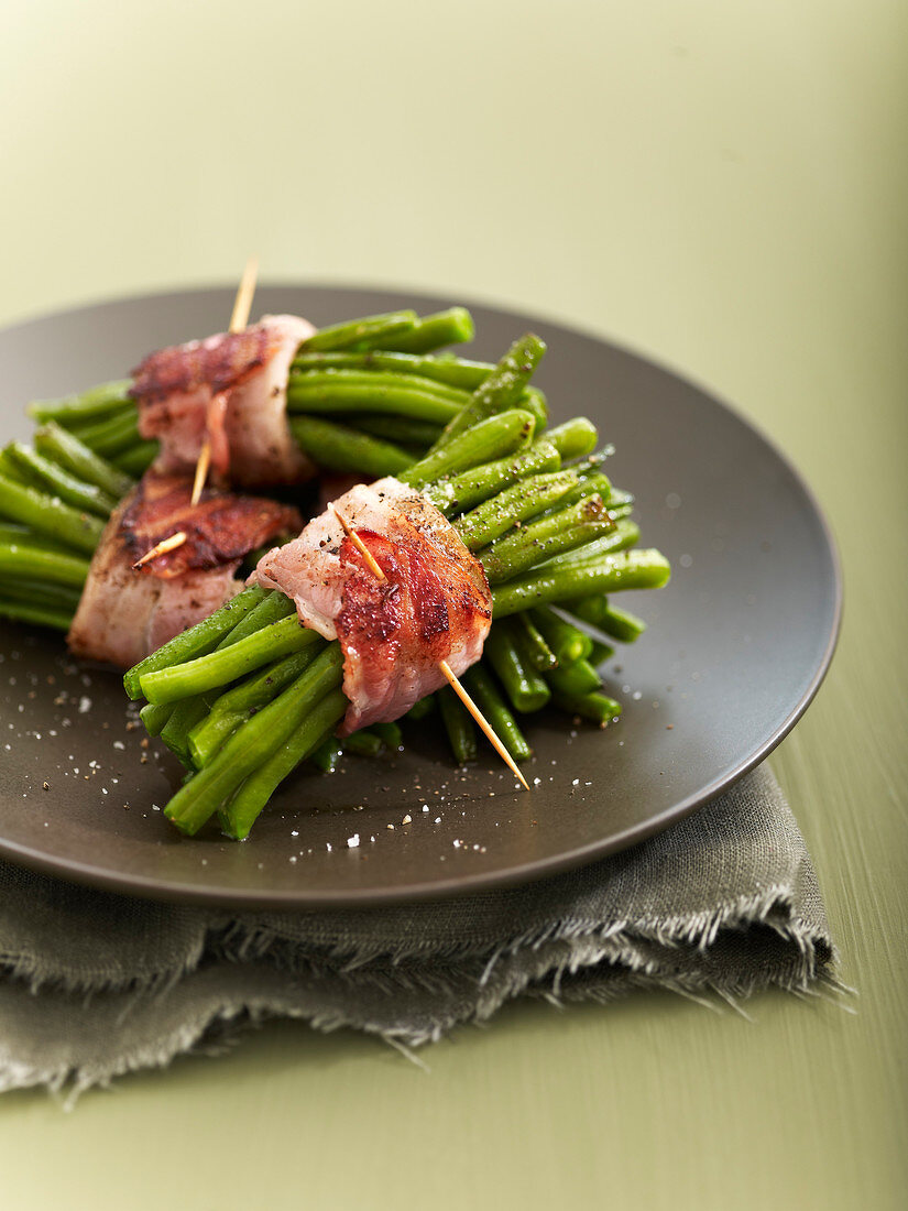Bundles of green bens tied with grilled strips of bacon