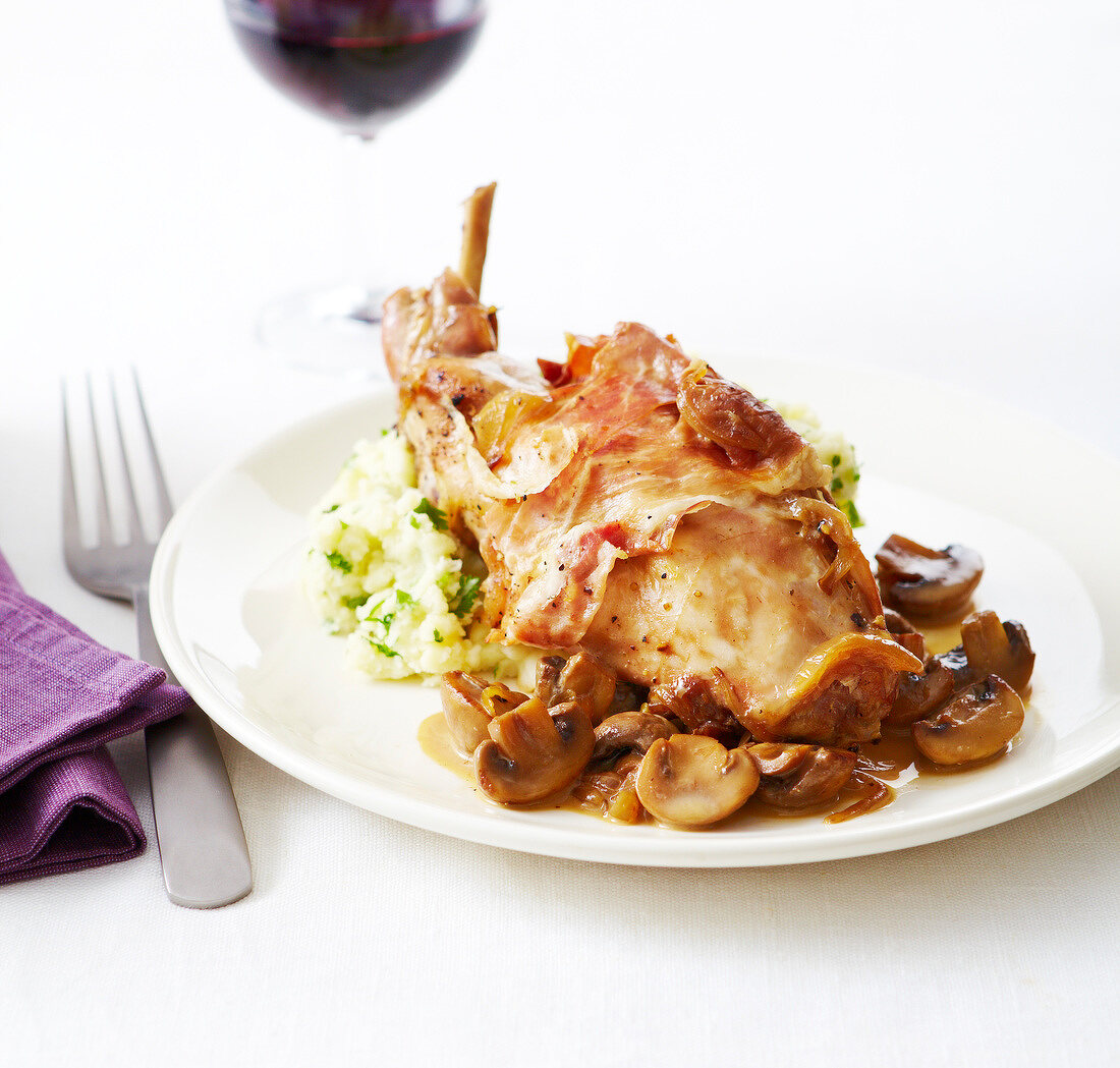 Kaninchen mit Pilzen und Rohschinken auf Stampfkartoffeln