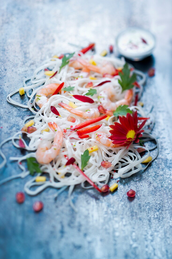 Rice noodle salad with king prawns, peppers and a red daisy