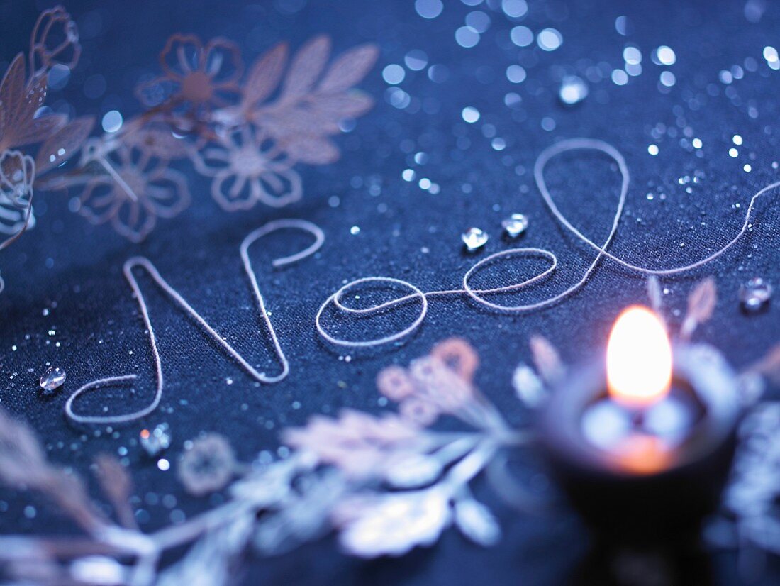 The word "Noel" written with string on a Christmas decorated table