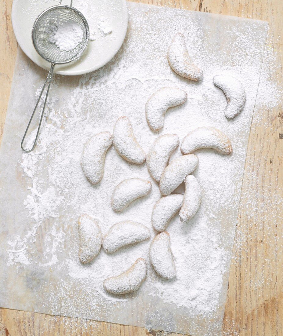 Plätzchen nach Art von Vanillekipferl mit Puderzucker bestreuen