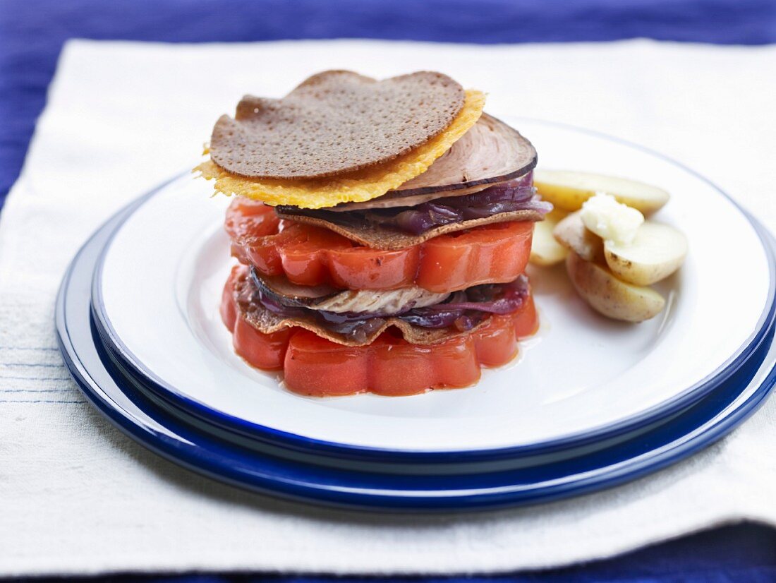 A stack of sliced beefsteak tomatoes, galette, andouille sausage from Guéméné and red cabbage