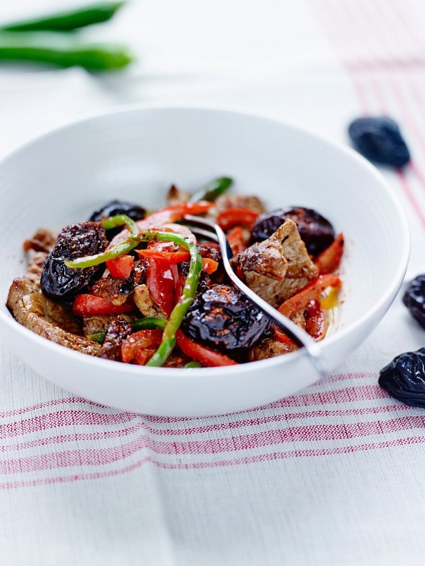 Sautéed pork with baked plums and red and green peppers