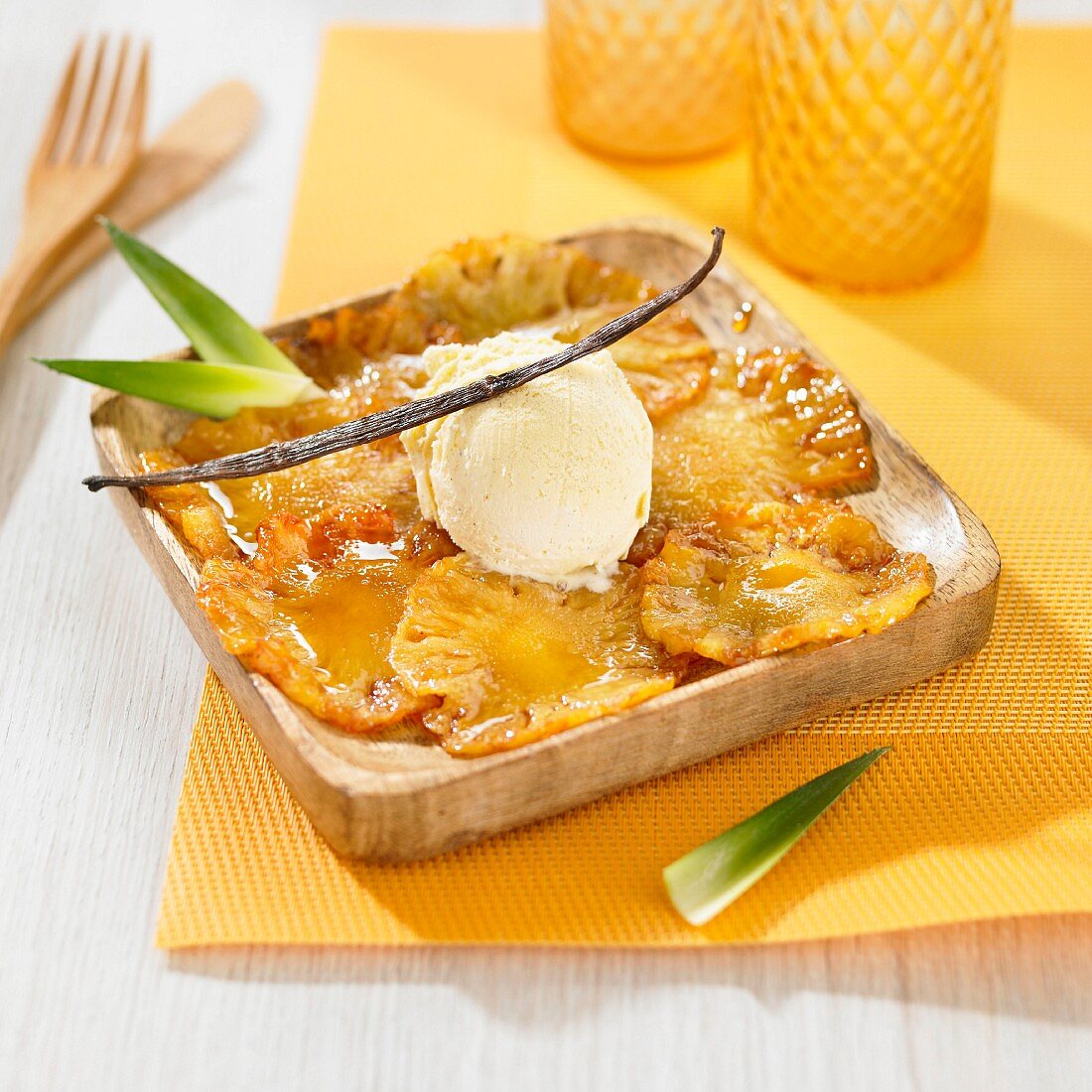 Thin slices of caramelized pineapple and a scoop of vanilla ice cream