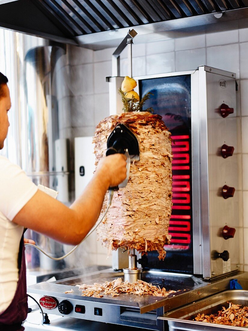 Mann schneidet Döner Kebab vom Drehspiess ab