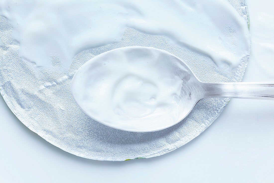 An aluminium lid and a spoon on fromage blanc