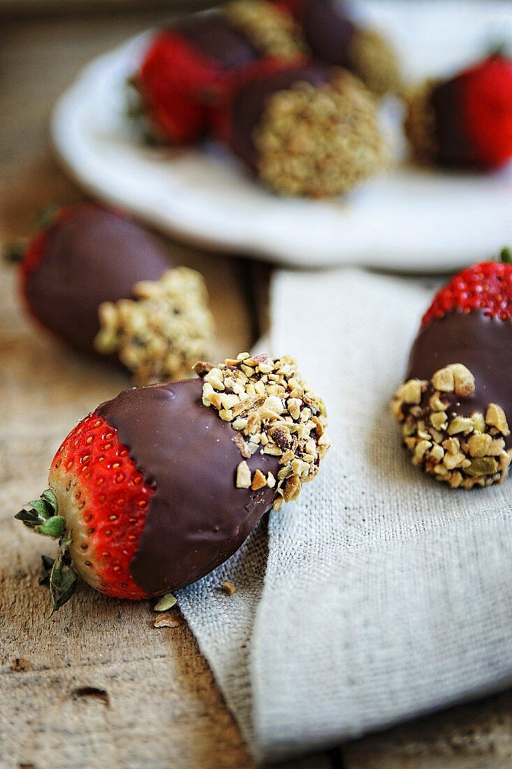 Erdbeeren mit dunkler Schokolade überzogen mit gehackten Haselnüssen
