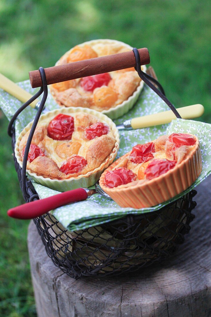 Clafoutis mit roten und gelben Kirschtomaten auf einem Drahtkorb im Freien