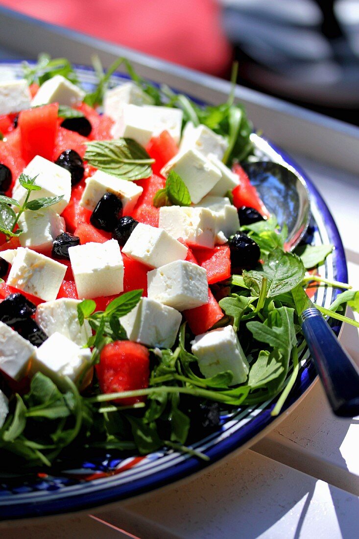 Rucolasalat mit Wassermelone, Fetakäse und schwarzen Oliven