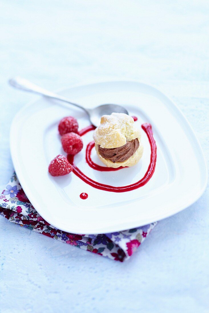 Chocolate mousse cream puff with raspberry coulis