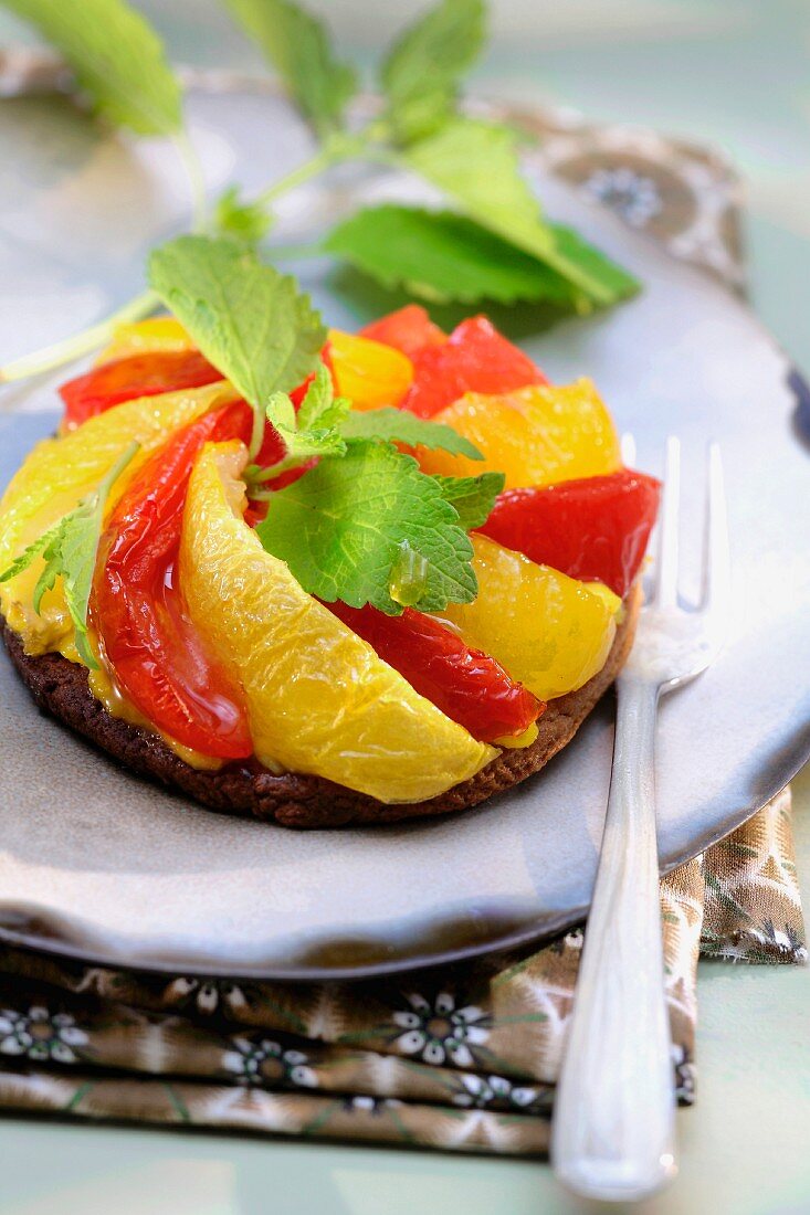 Red and yellow stewed tomato tatin tart with lemon balm