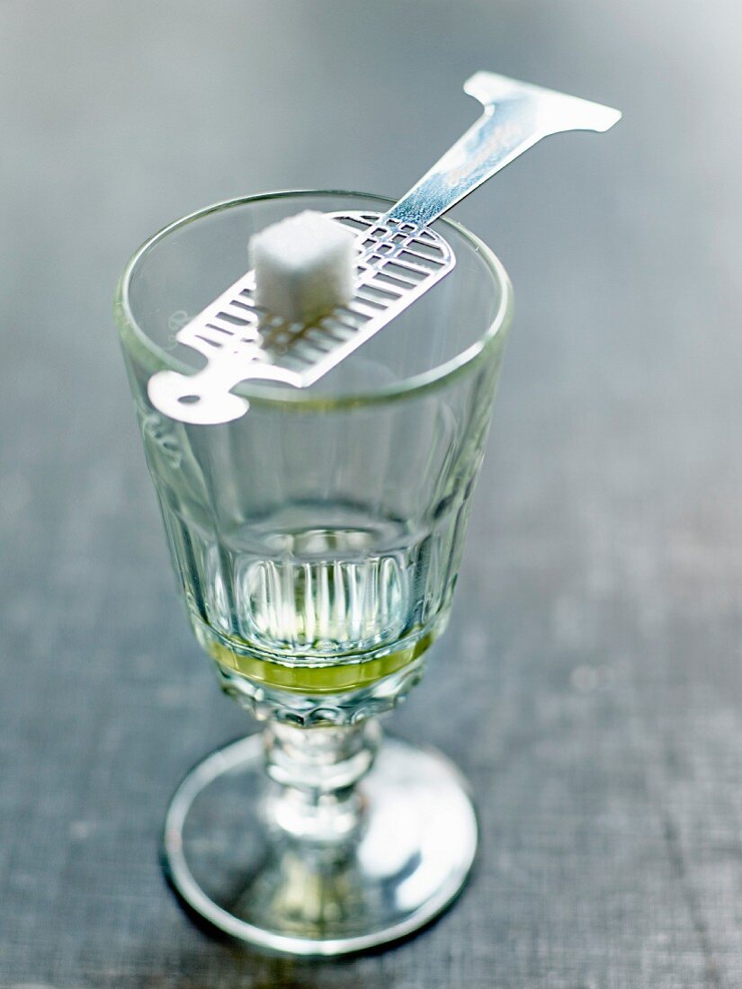 Absinth im Glas mit Zuckerwürfel auf einem Absinthlöffel