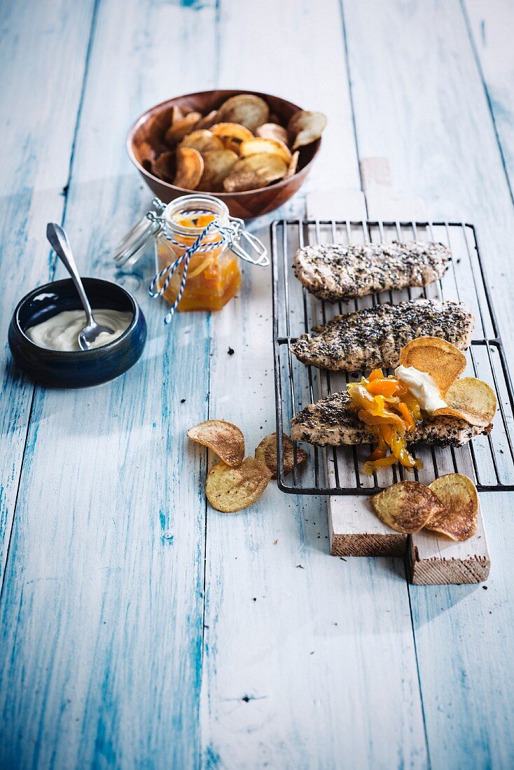 Hähnchenschnittel mit Kräutermarinade auf einem Grillrost, Chips und Orangenchutney