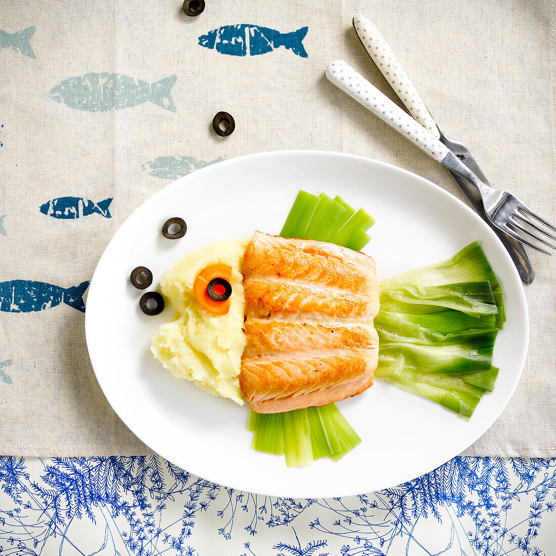 Fish-shaped plate of salmon, leeks and black olives