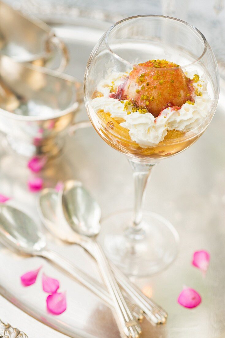 Peach Melba with whipped cream,crushed pistachios and raspberry coulis