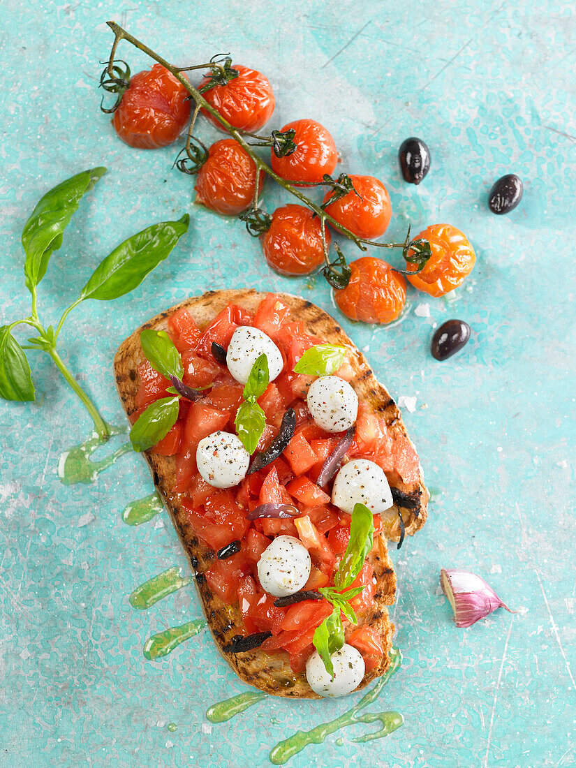 Bruschetta aus Tomaten, Mozzarella, Basilikum und schwarzen Oliven