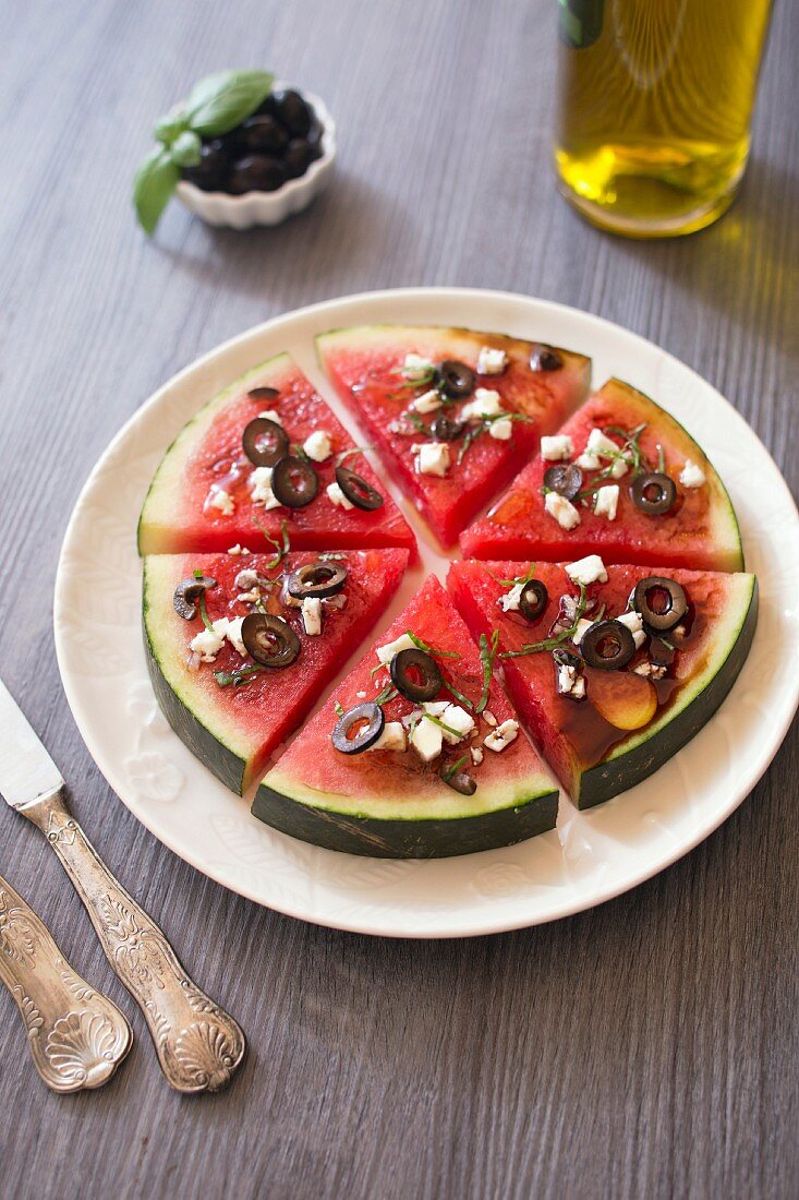 Wassermelone mit Feta und schwarzen Oliven nach Art einer Pizza