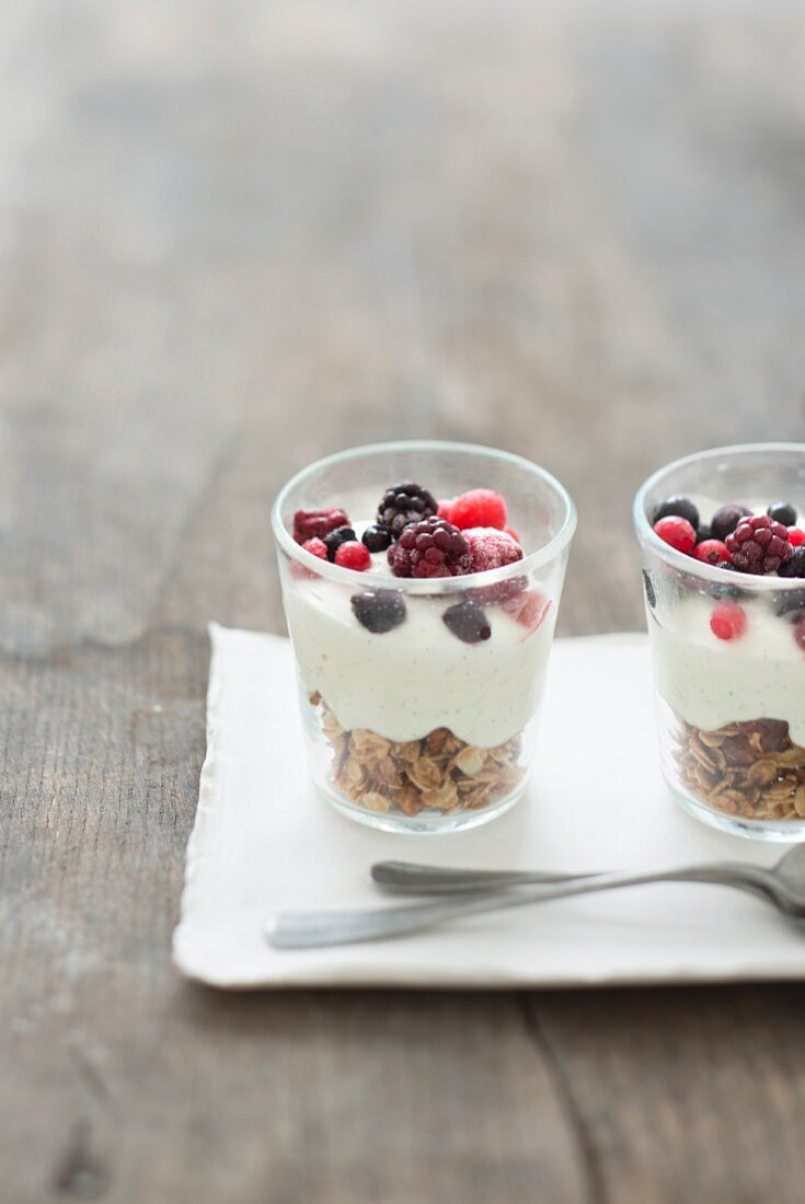 Haferflocken mit Vanillejoghurt und Waldfrüchten im Glas serviert