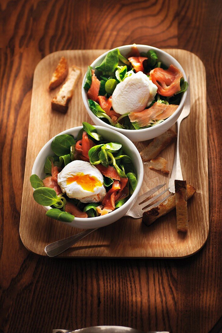 Corn lettuce and smoked salmon salad garnished with a soft-boiled egg