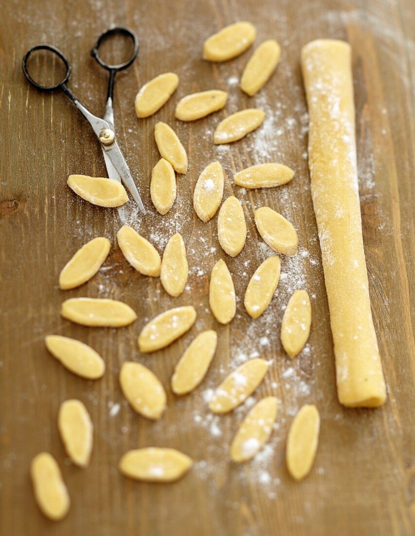 Cutting the rolls of orecchiette dough into small bits with scissors