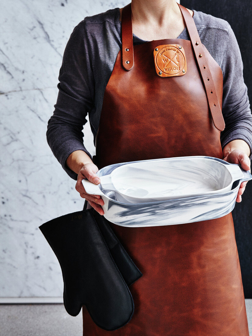 Woman wearing a leather apron and carrying empty dishes