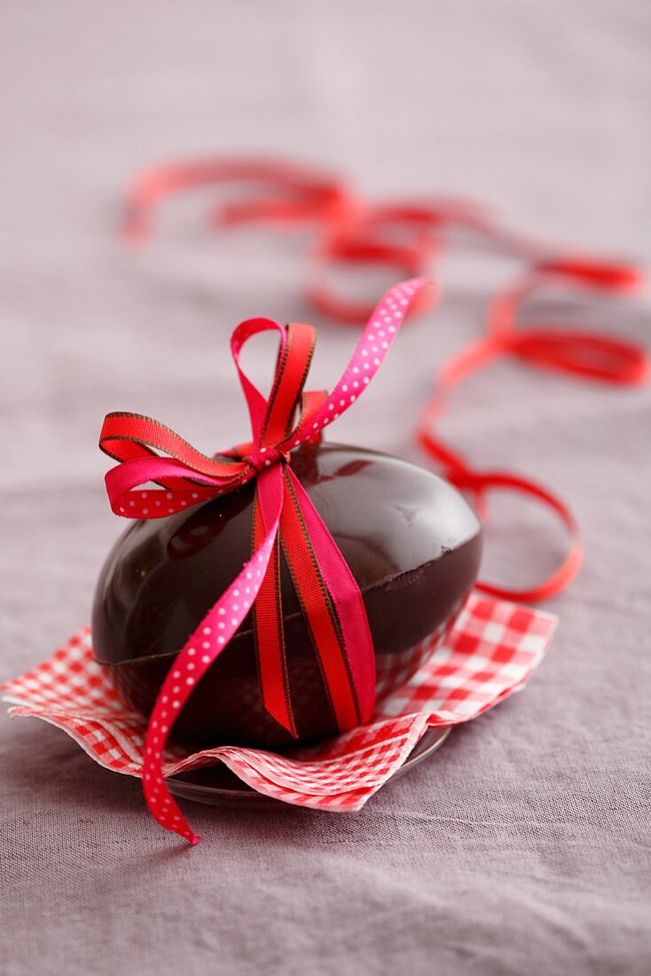 A chocolate egg tied with a red bow