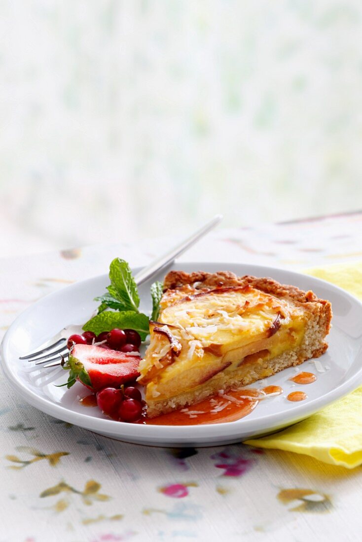 Ein Stück Kokos-Nektarinen-Clafoutis mit Waldfruchtsirup