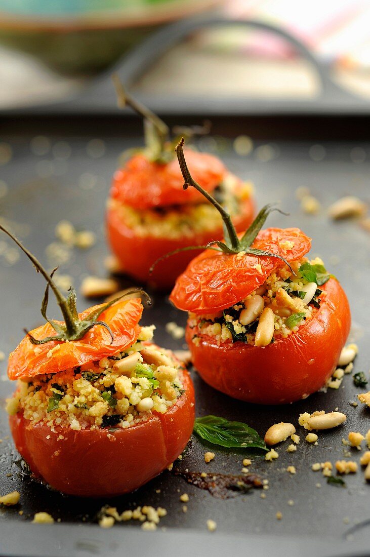 Stuffed tomatoes topped with crushed pine nuts and basil