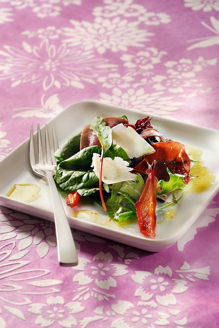 Salat mit jungem Spinat, Parmesan, Rohschinken, Tomate und getrockneten Paprika