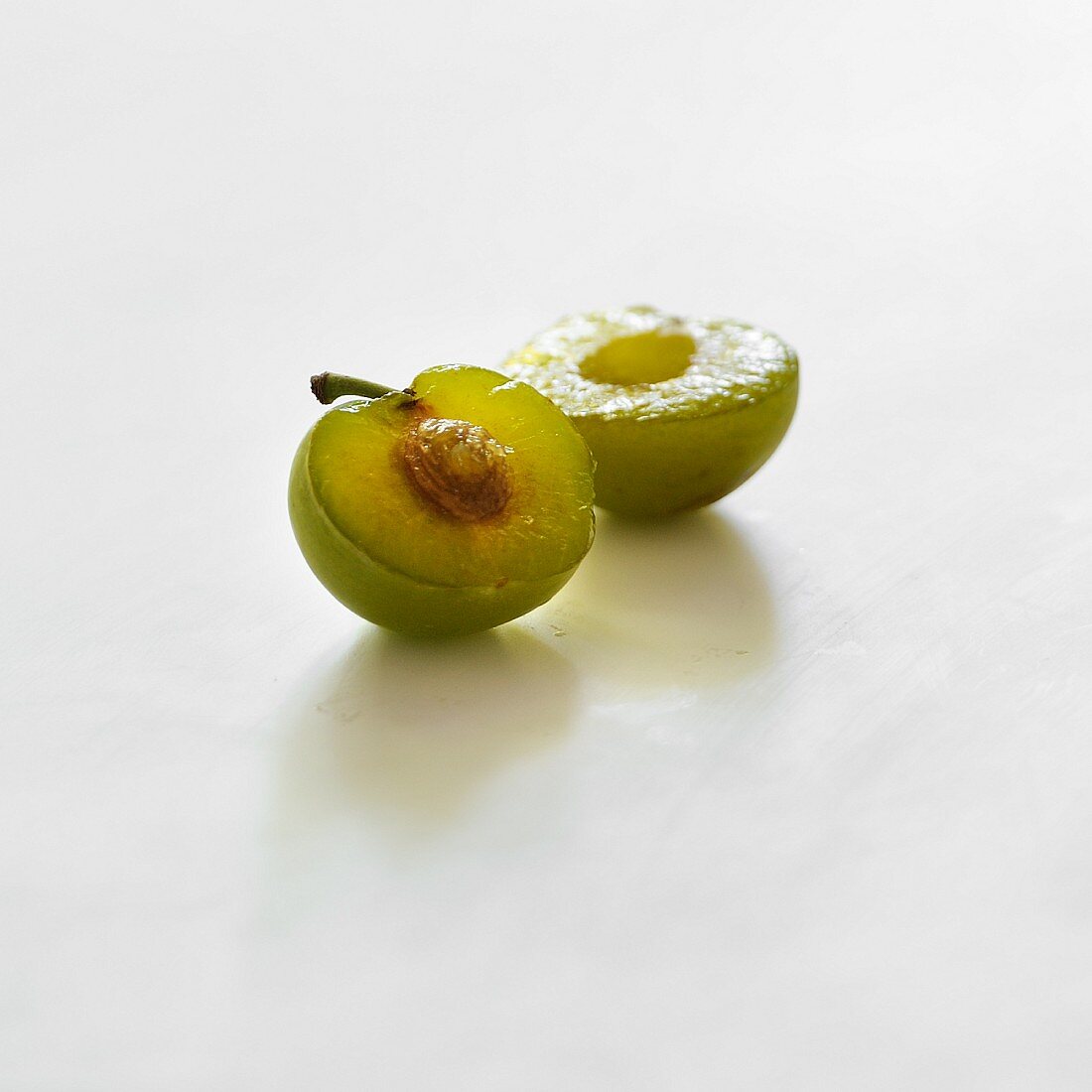 Greengage plum halves on a white background