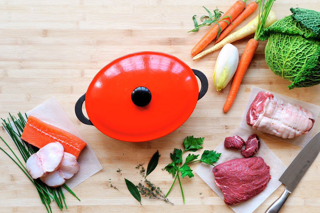 Stillleben mit Gemüse, Kräutern, rohem Fleisch und Fisch und Schmortopf