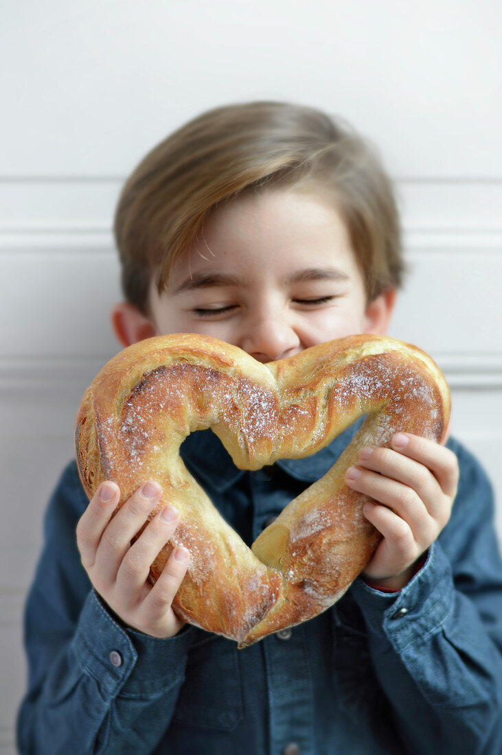 Child kissing a heart-shaped bread